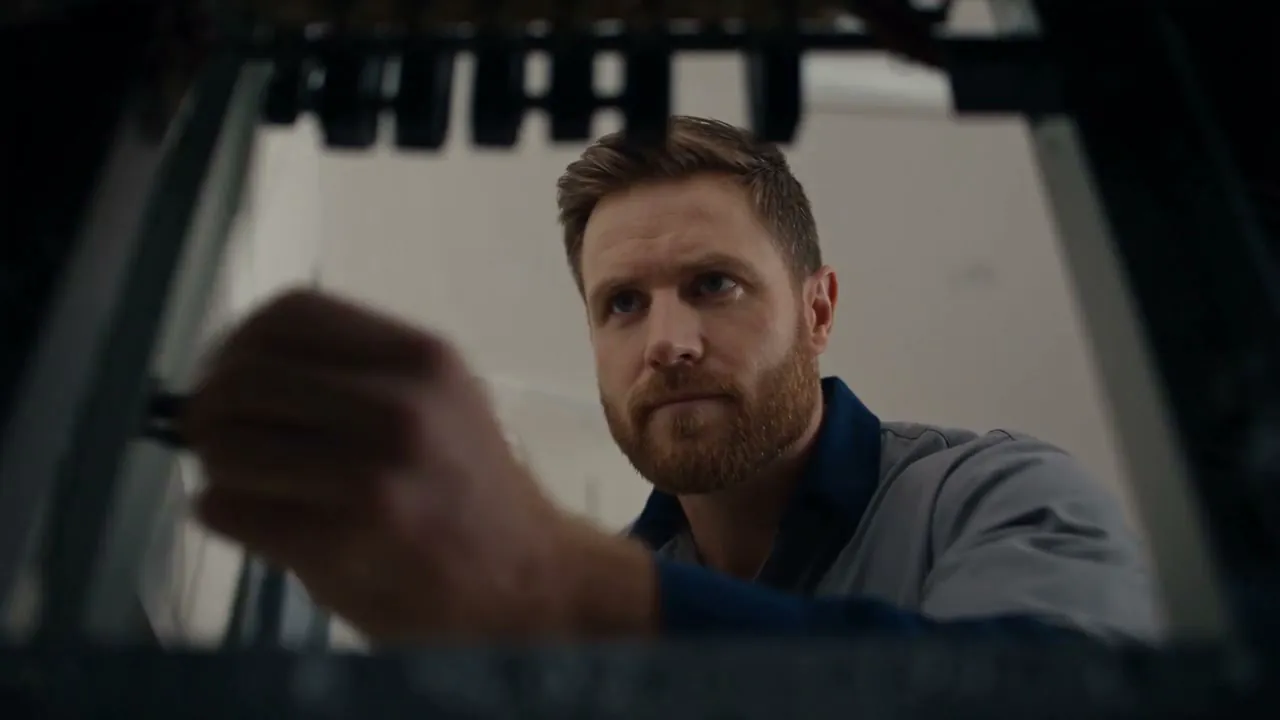 Nathan isolating a switchboard, reaching up into the open cabinet with a screwdriver in hand